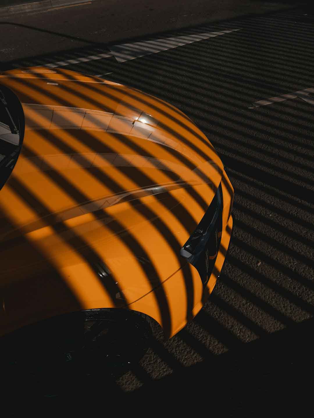 A car with a newly applied carbon fiber wrap, parked in sunlight