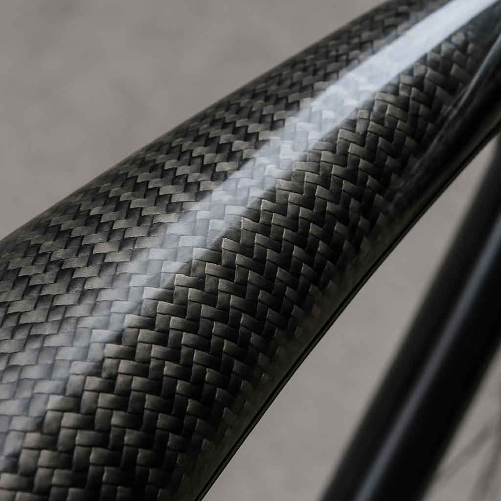 A close-up shot of a carbon fiber weave pattern on a bike frame, showing the texture of the raw material under a clear coat